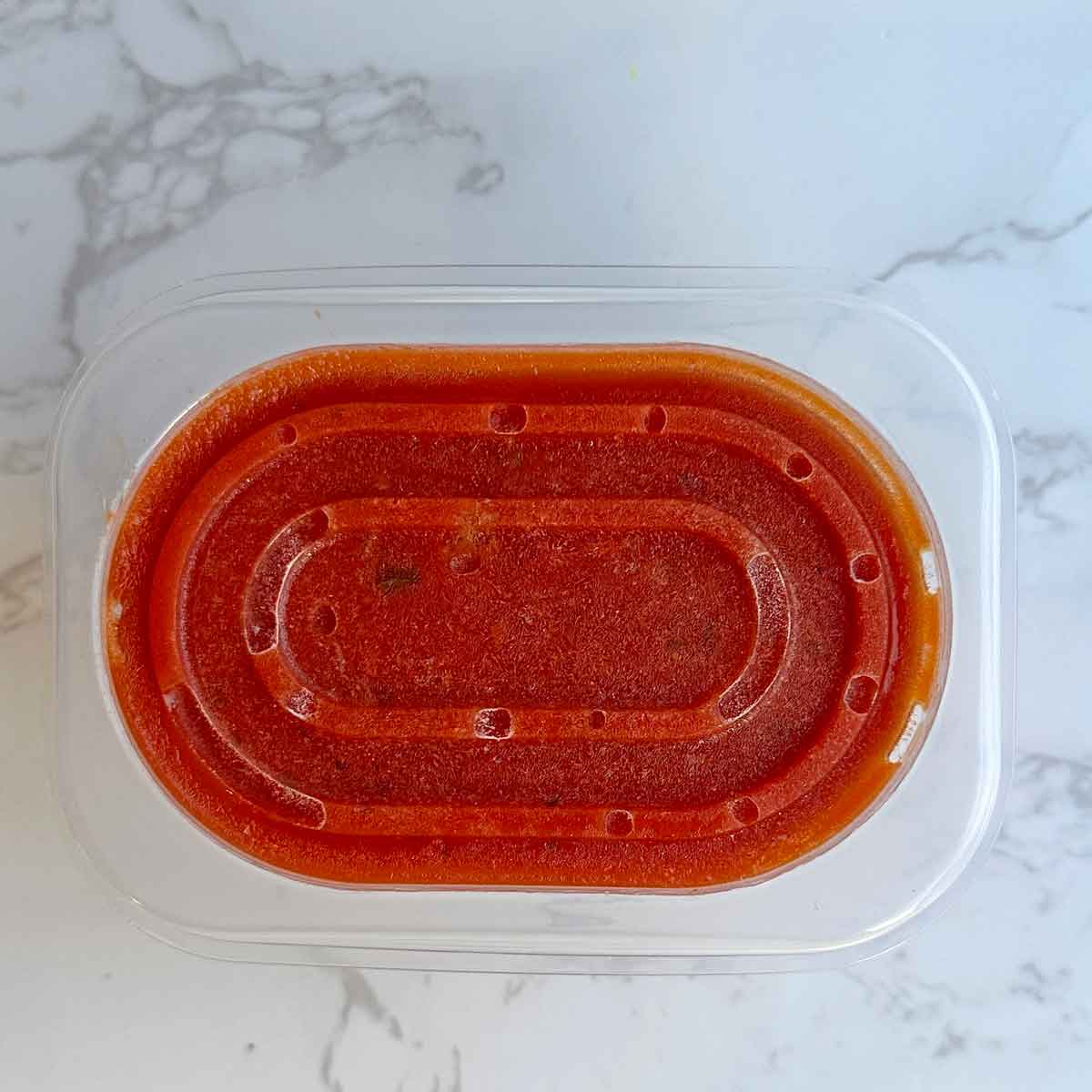 frozen pasta sauce in a container.